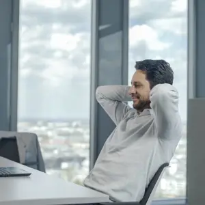 Man Sitting In Office With Hand Behind Head
