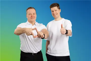 Two Employees Of Fsas Technologies Oy Posing Together Against Blue Background