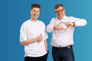 Two Employees Of Fsas Technologies Oy Posing Together Against Blue Background