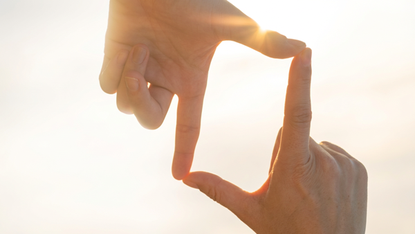 Two Hands Forming Rectangular Frame Against Bright Background (1)