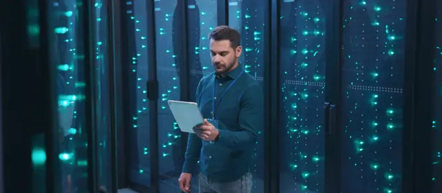 Man With Tablet in a dark data center
