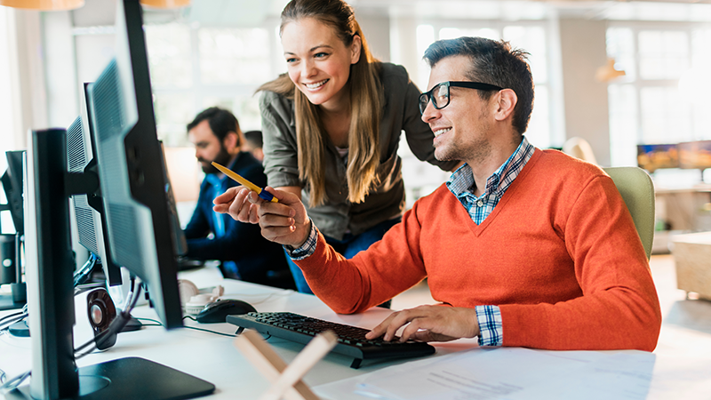 Man And Woman Looking At Work Desk Screen